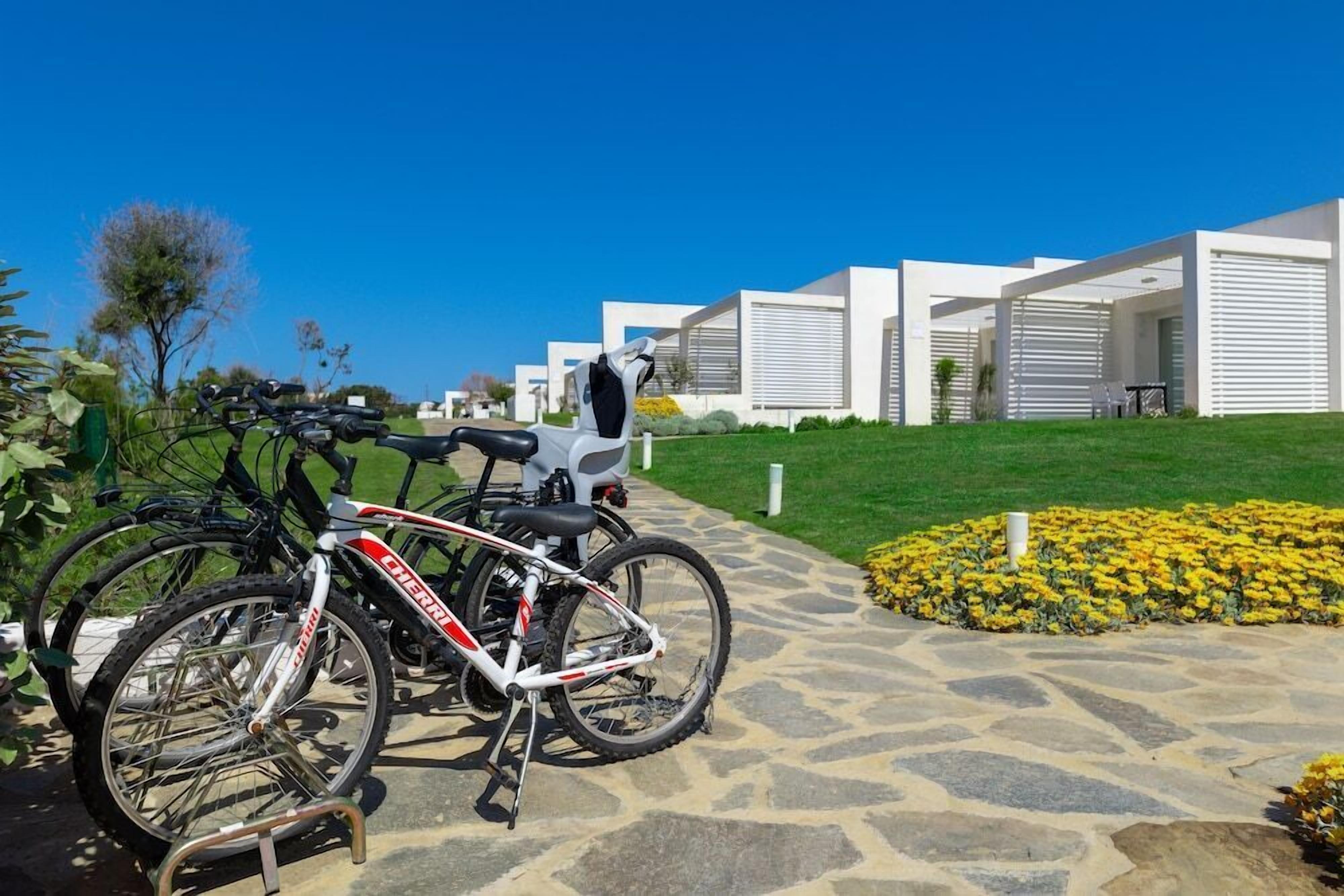 Un edificio moderno con un'area esterna coperta, una bicicletta e un aiuola.