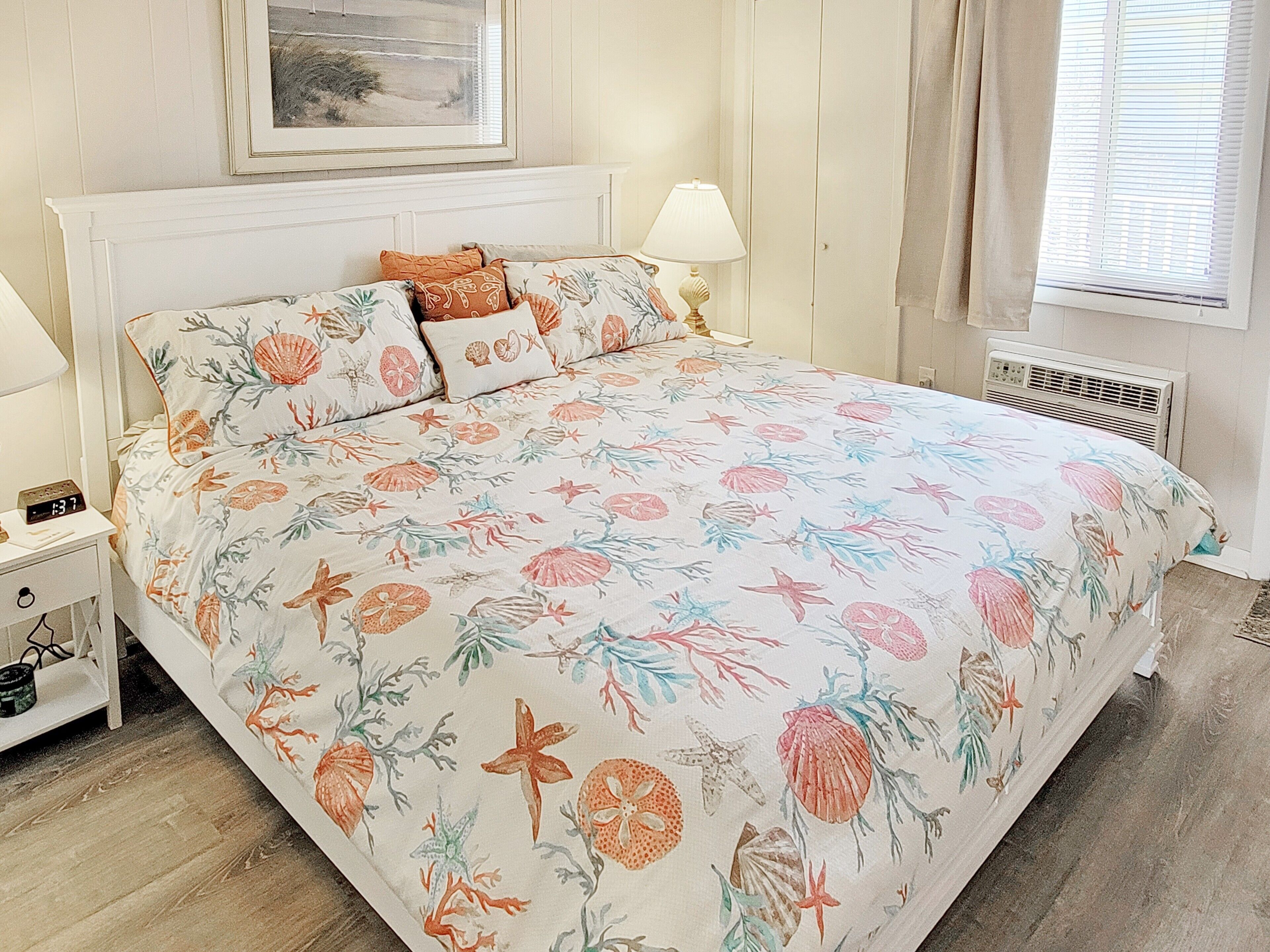 Ein Schlafzimmer mit Bett, Nachttisch, Lampe und einem gerahmten Bild an der Wand.