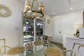 Una cocina moderna con una mesa de vidrio, sillas de mimbre y una lámpara colgante.