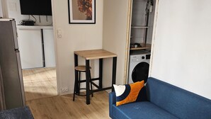 Um espaço compacto com sofá, mesa pequena, televisão e cozinha compacta.