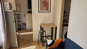 Um espaço de estar compacto com sofá, uma mesa pequena, um relógio e um quadro na parede.