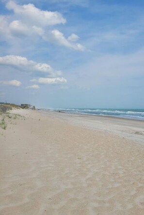 Une vaste plage de sable fin, avec des vagues douces et un ciel dégagé.