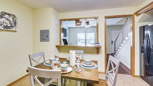 A dining area with a wooden table set for four, surrounded by white chairs. A mirror hangs on the wall above the table, reflecting the room. - 1 Mi to Pleasure Pier! Charming Galveston Retreat (Galveston)