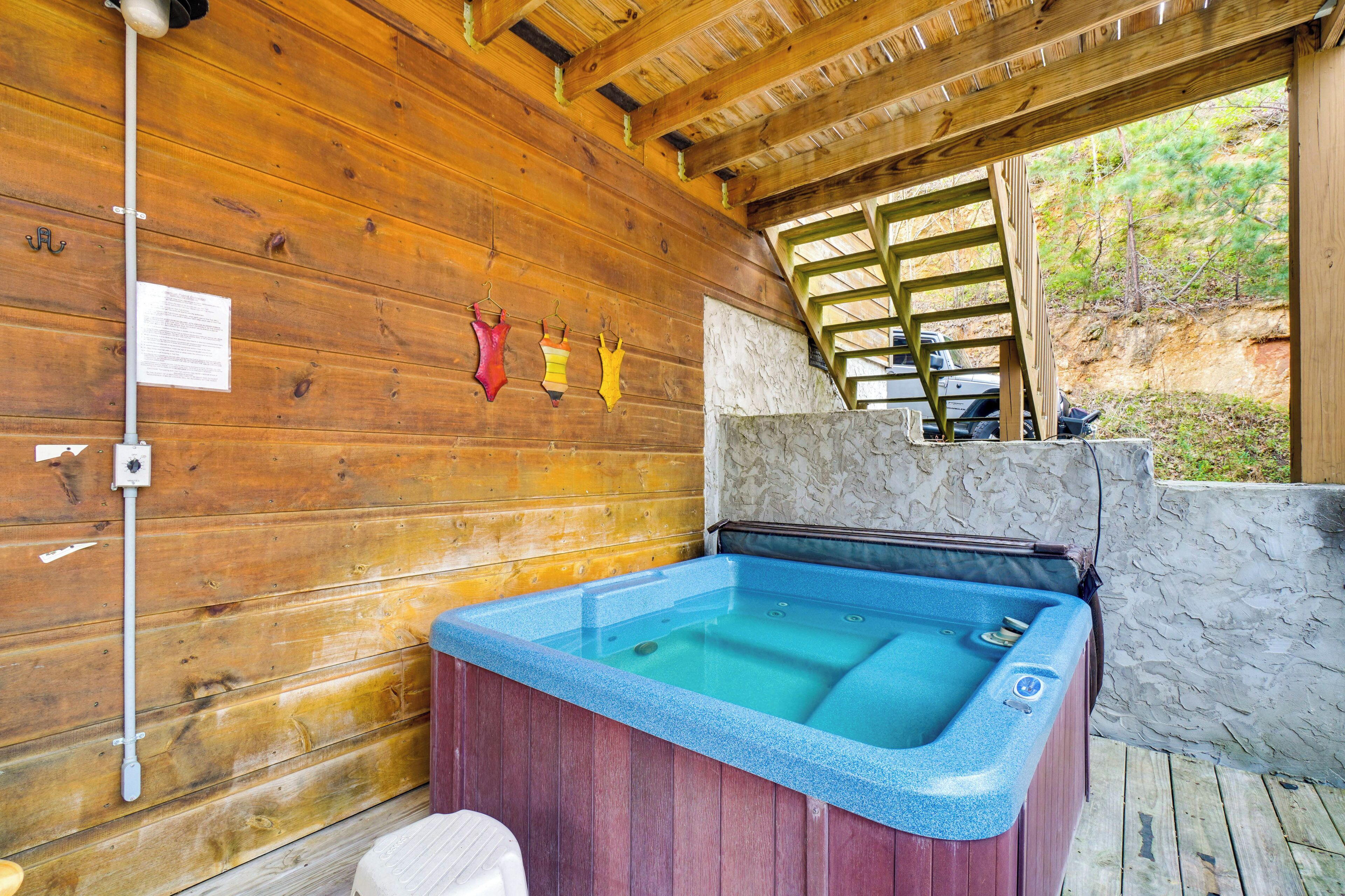 Una cabaña de madera con hidromasaje, paredes de madera y un muro de piedra.
