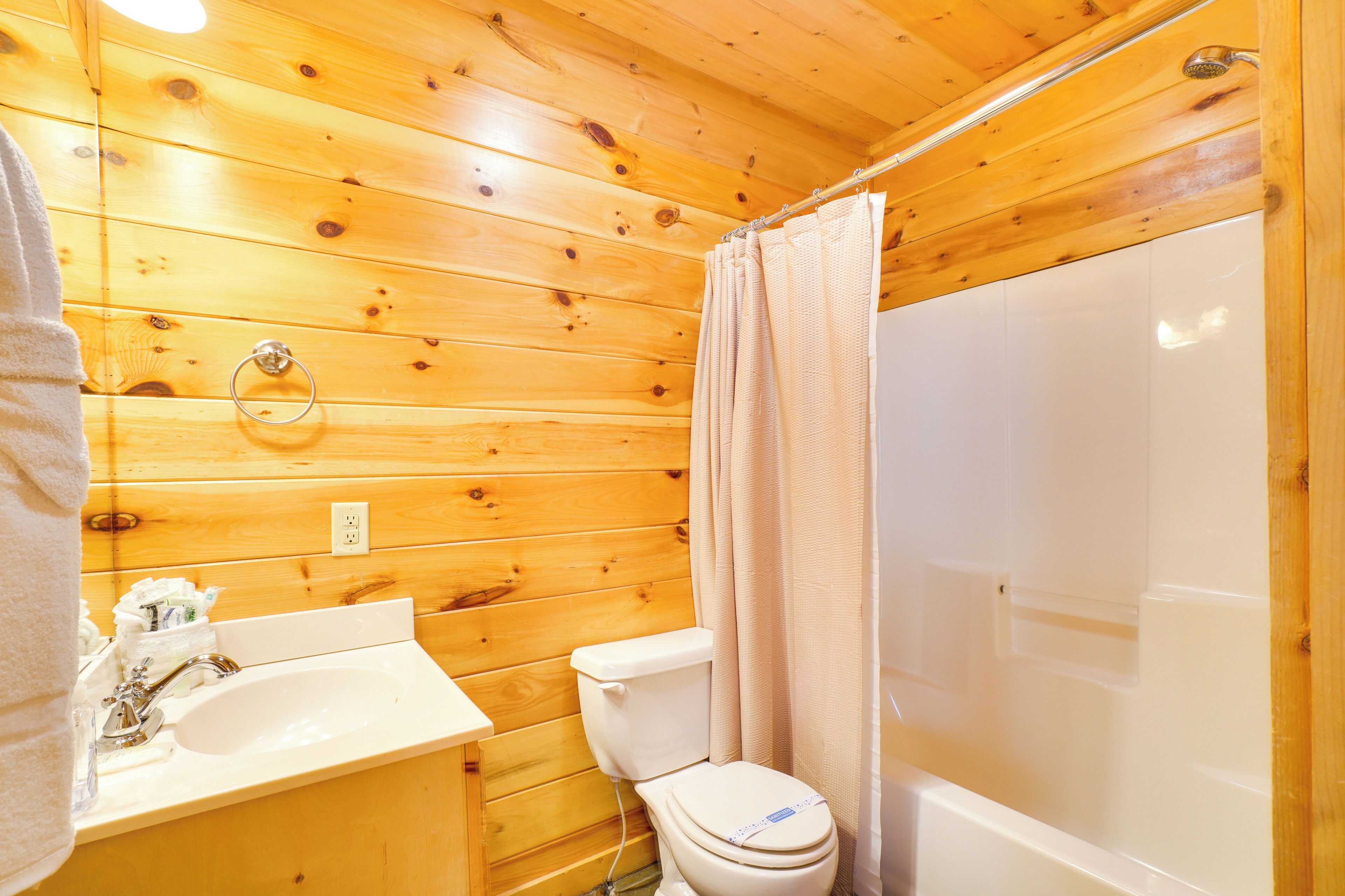 Een badkamer met houten lambrisering, een wastafel, toilet en douche.