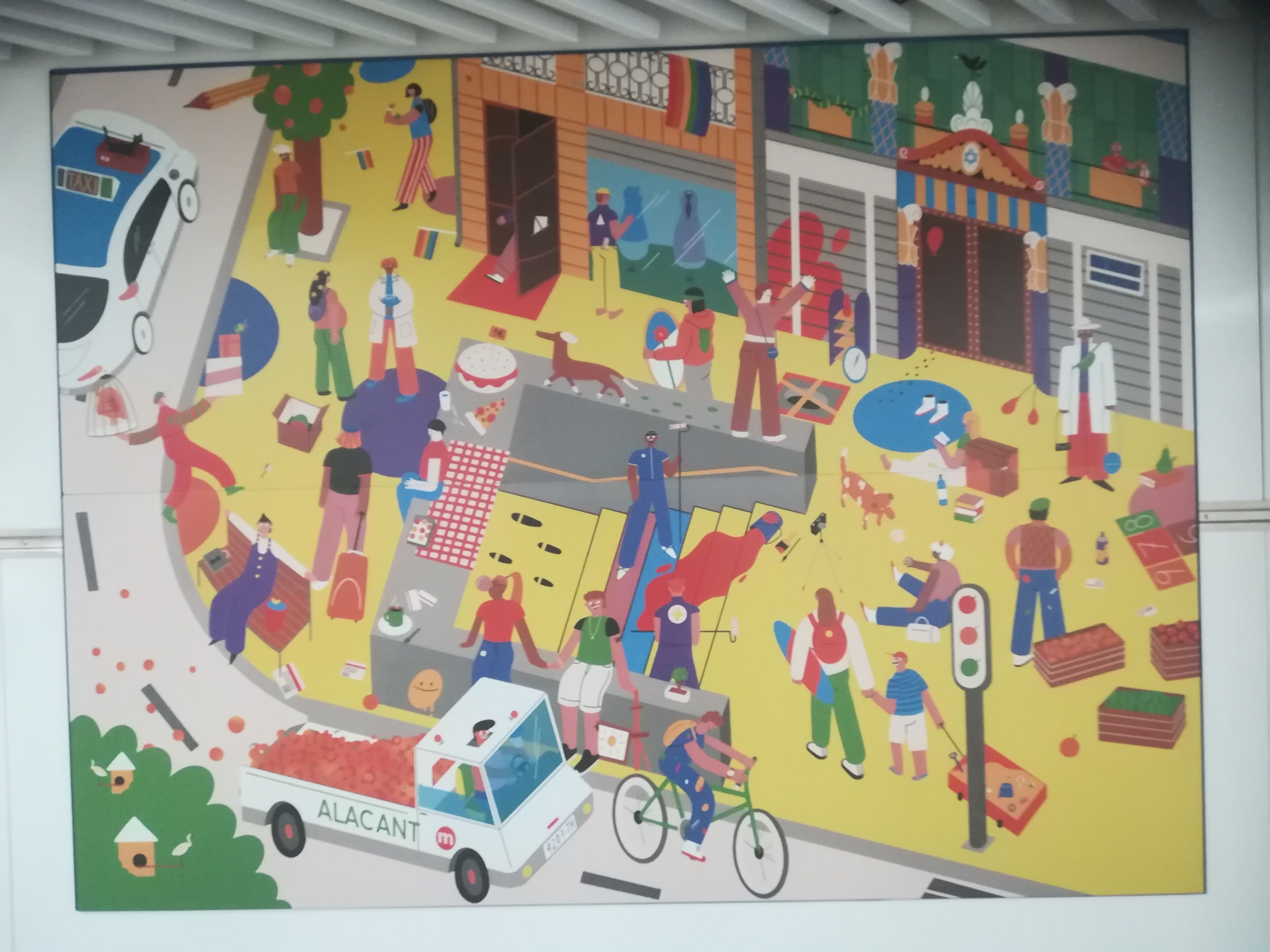 A colorful mural with various people and objects, including a taxi, a bicycle, and a truck labeled "ALACANT."