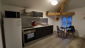 Una cocina compacta con electrodomésticos modernos, un comedor con dos sillas y vistas a través de una ventana.