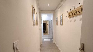 Un pasillo estrecho con piso de madera, paredes blancas y una puerta a la derecha.