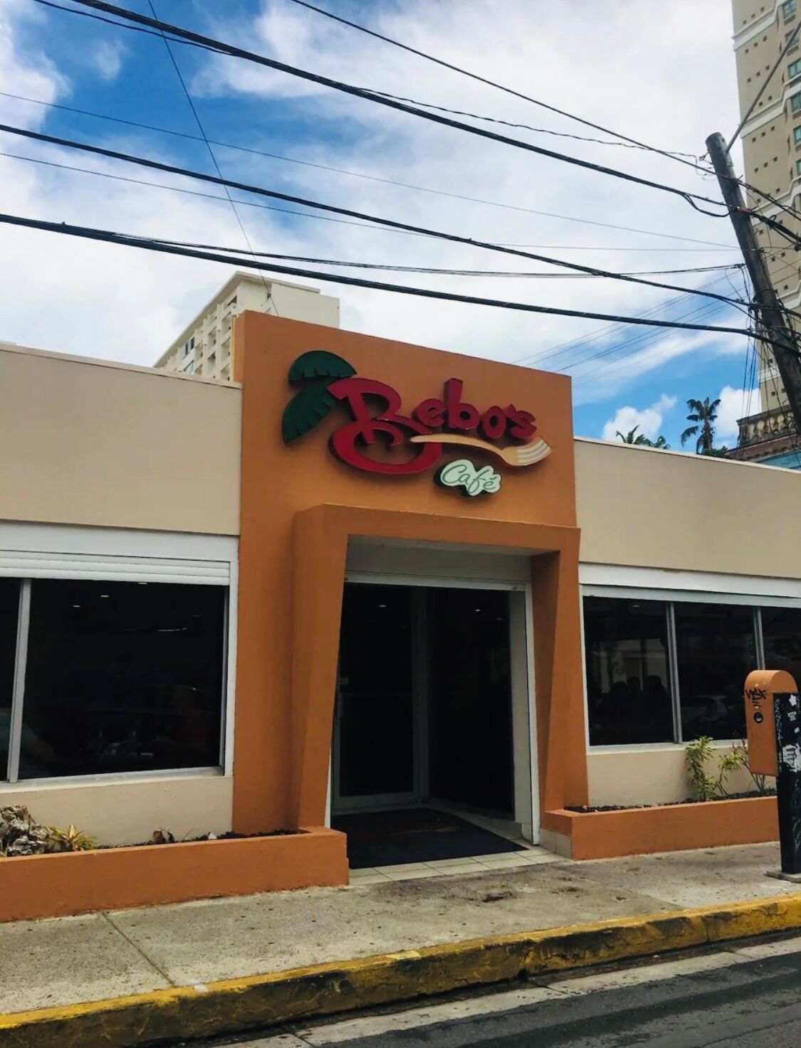 Un bâtiment sur lequel on peut lire l’inscription « Bebos Cafe » et qui arbore un logo représentant un palmier.