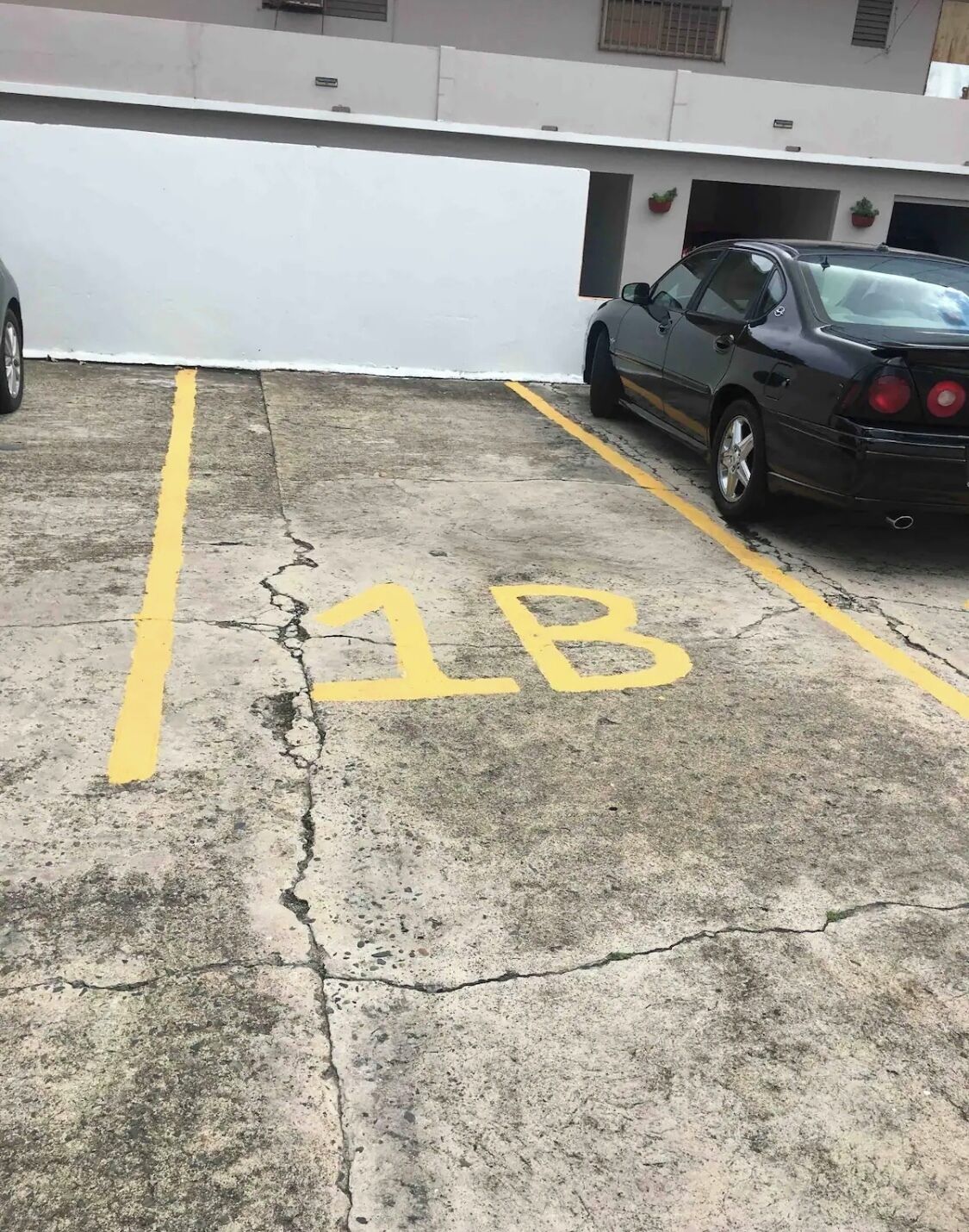 A parking area with a car parked in a spot marked '1B'.