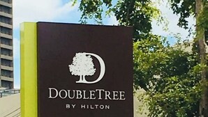 Placa do Doubletree by Hilton com o logotipo de uma árvore e o nome 'Café Pierre'.