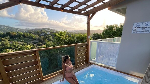 A wooden deck with a hot tub and a view of the countryside.