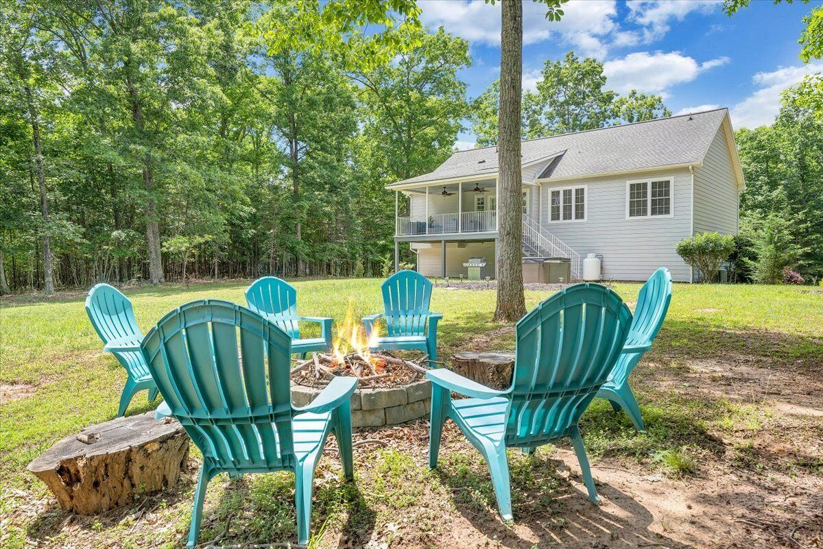 A house with a fire pit and four chairs in a backyard.