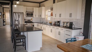 A modern kitchen with white cabinets, a stainless steel refrigerator, a built-in oven, and a coffee maker. - Breathtaking Mountain Views in La Union, El Salvador. Escape to serenity (Anamorós)