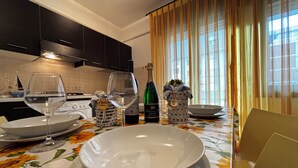 A dining table set with plates, glasses, and bottles, with a laptop on the right. - Comfortable Flat in Bibione - Beahost (Rosolina)