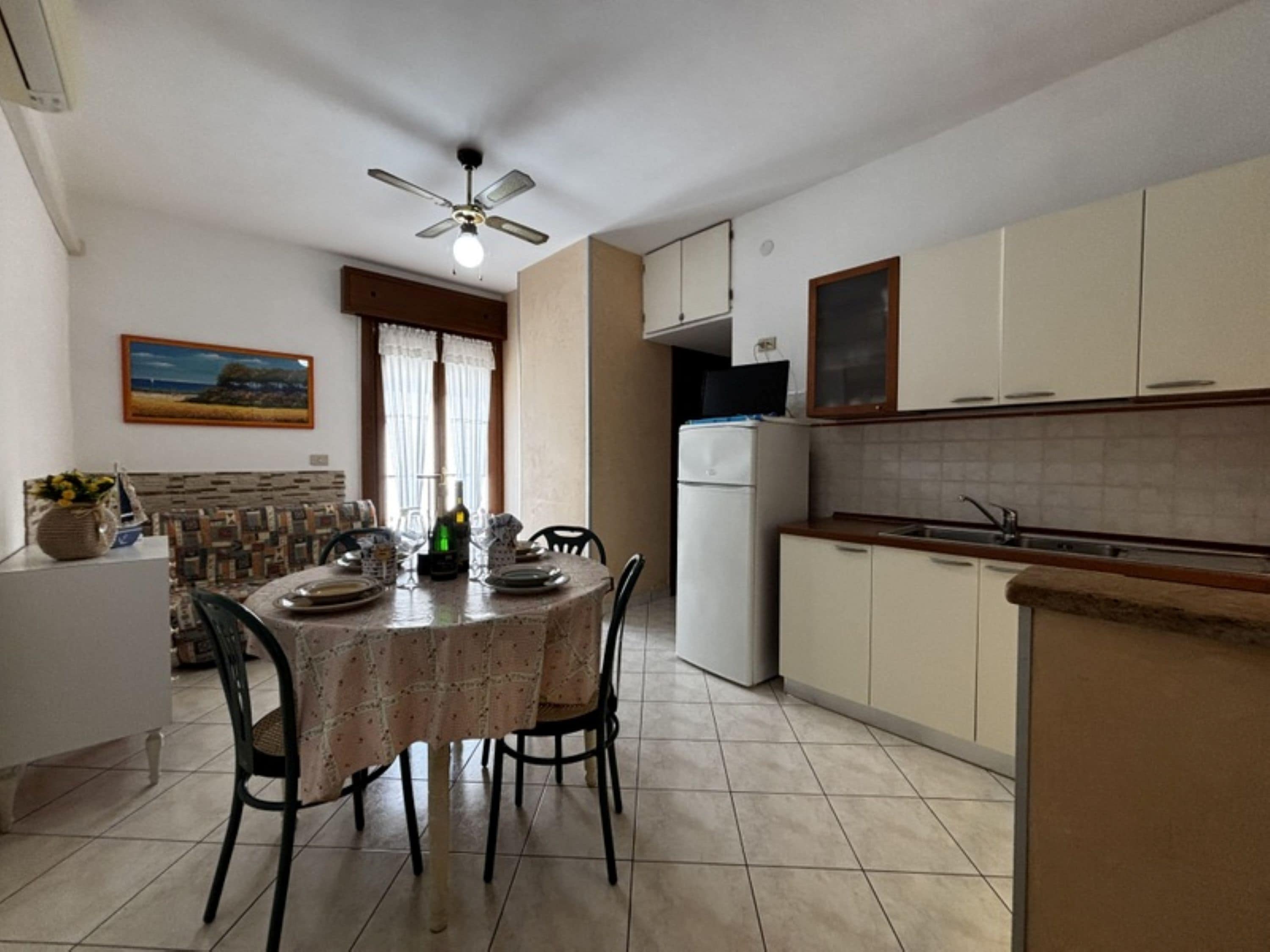 Une cuisine de taille réduite comprenant un coin repas, un ventilateur de plafond et un réfrigérateur.