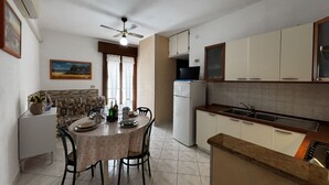 A compact kitchen with a dining table, chairs, a refrigerator, and a microwave. - Renovated Apartment in Rosolina (Rosolina)