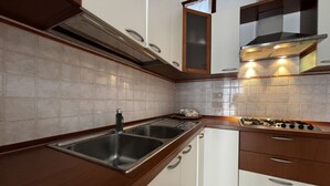 A kitchen with a double sink, a stove, and wooden cabinets. - Renovated Apartment in Rosolina (Rosolina)