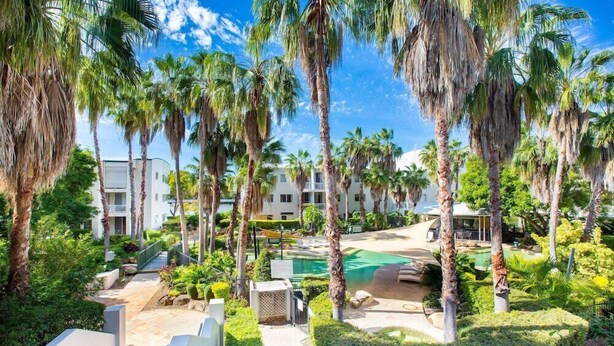A resort with palm trees, a pool, and a pathway leading to the buildings. - Bridgewater Terrace (Brisbane)