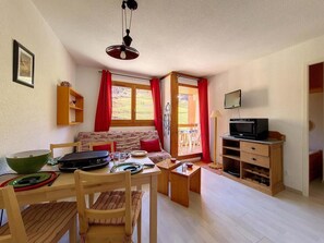 A cozy living room with a sofa, dining table, and TV stand.