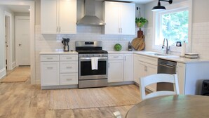 Une cuisine moderne avec des meubles blancs, des appareils en acier inoxydable et une table à manger en bois.