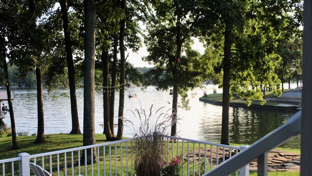 Une terrasse avec des chaises donnant sur un lac, entourée d’arbres.