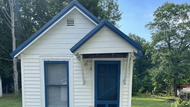 A small, single-story house with a blue door and window, a wooden porch, and a grassy yard. - Quaint Cabin #7 - Pymatuning Lake (Jamestown)