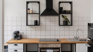 Een moderne keuken met een houten aanrecht, een ingebouwde oven, een koffiezetapparaat en zwarte wandplanken.
