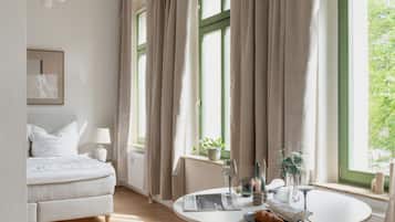Ein modernes Schlafzimmer mit Bett, Nachttisch, Lampe und Blick auf Grün.