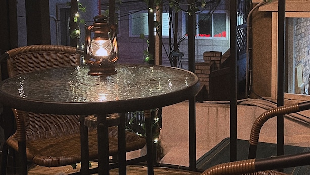 An outdoor patio with wicker furniture, string lights, and a lantern. - Jnineguesthouse (Seoul)