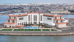 A large, multi-story hotel with a central courtyard and a swimming pool.