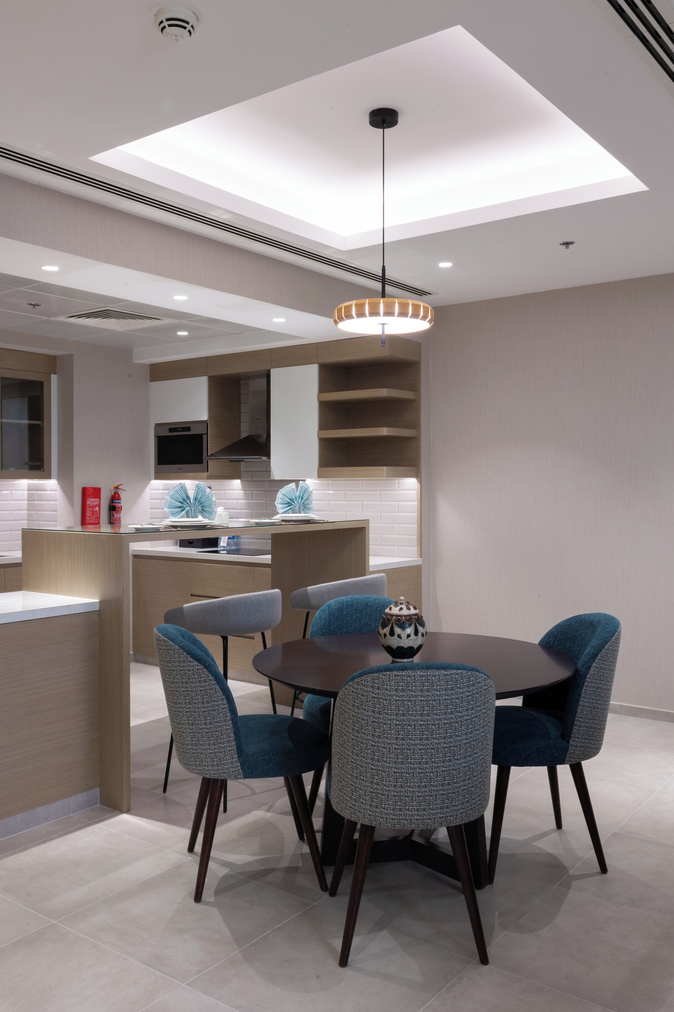 A modern kitchen with a central island, built-in appliances, and a dining area with a round table and chairs.