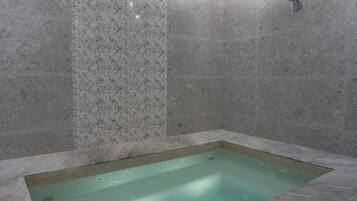 Relax in a serene spa area featuring a hot tub surrounded by a decorative tile floor.