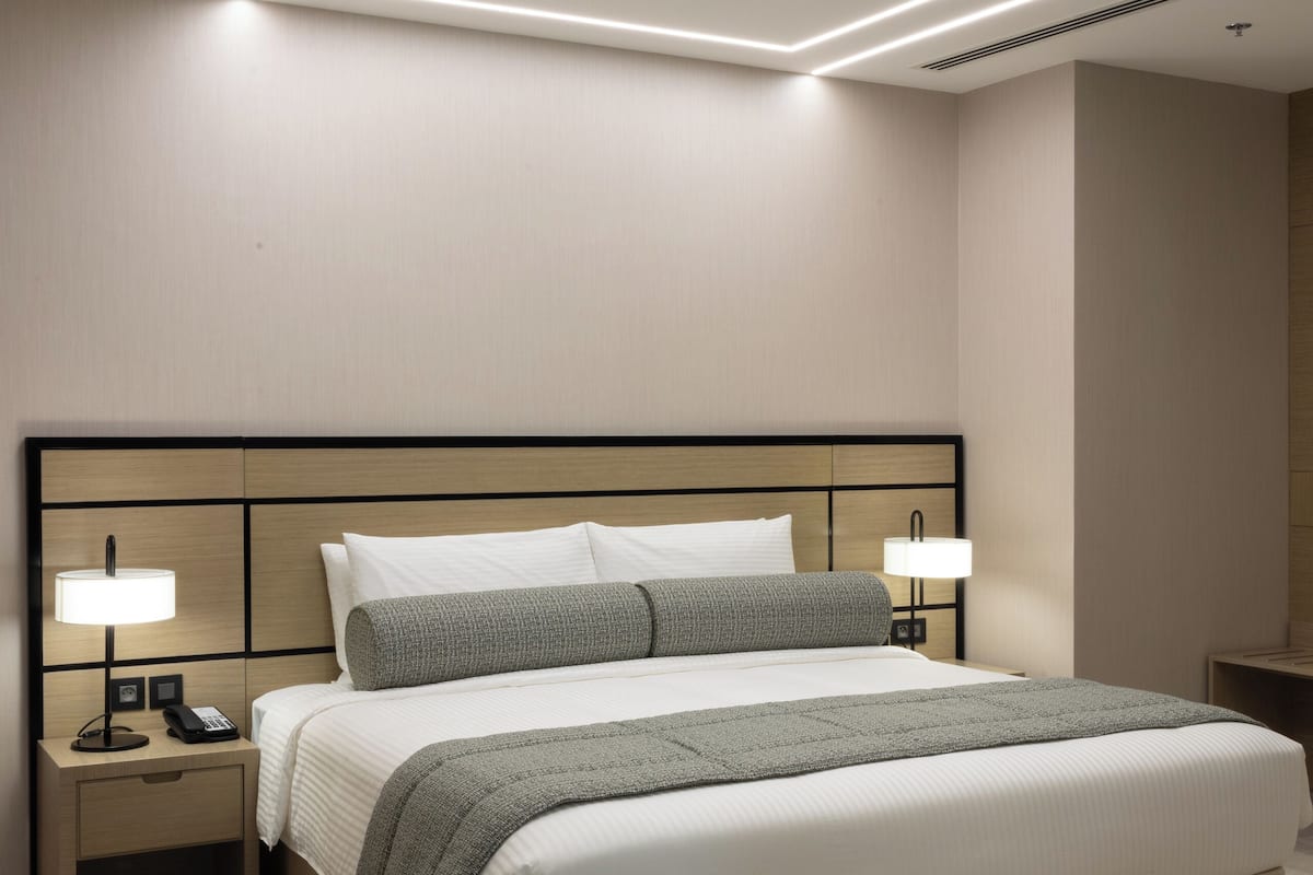 Une chambre d’hôtel moderne avec un grand lit, des lampes de chevet, une table de chevet et un luminaire au plafond.