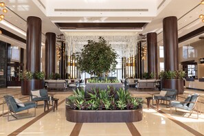 Experience the grandeur of our lobby, featuring dark columns, lush greenery, and comfortable seating areas.