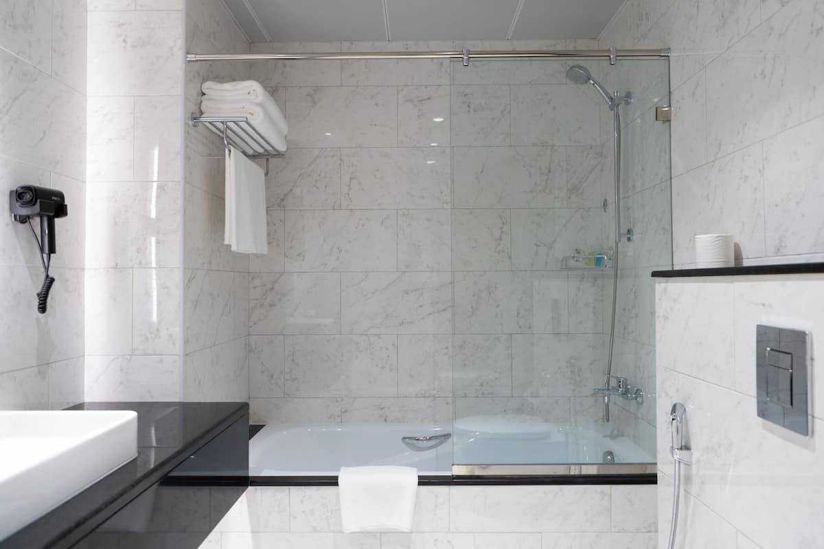 Une salle de bain moderne dotée d’une douche à parois de verre, d’une baignoire et d’un meuble-lavabo avec un porte-serviettes.