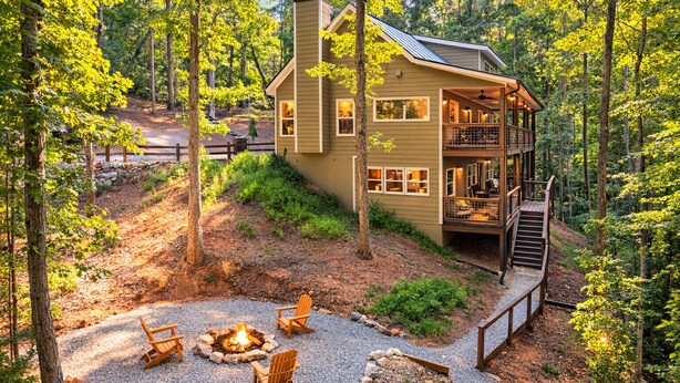 A cabin with a deck, a fire pit, and outdoor seating.
