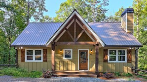 A cabin with a gabled roof, wooden exterior, and a chimney.