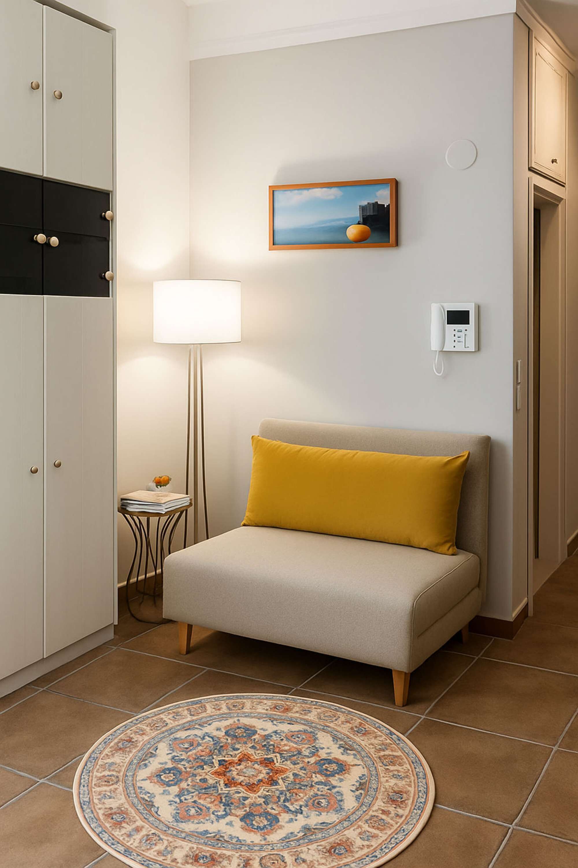 Une pièce comprenant un canapé, une lampe, un tableau, un téléphone et un tapis à motifs.