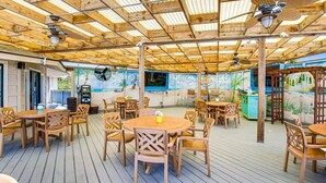 An outdoor patio area with wooden tables and chairs, ceiling fans, and a mural on the wall. - Beachfront Villa W/ Pool & Tennis Hilton Head (Hilton Head Island)