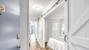 A hotel room with a bed, a wardrobe, a door with a lock, and a view of the outside. - Beachfront Villa W/ Pool & Tennis Hilton Head (Hilton Head Island)