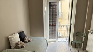 Ein Schlafzimmer mit einem Bett, Kissen, einem Sessel und Blick auf den Balkon.