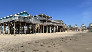 A beachfront property with multiple wooden structures supported by stilts, featuring balconies and a clear view of the ocean. - House and Toes in the SAND. No cars on this beach area! Vacation of a lifetime! (Freeport)