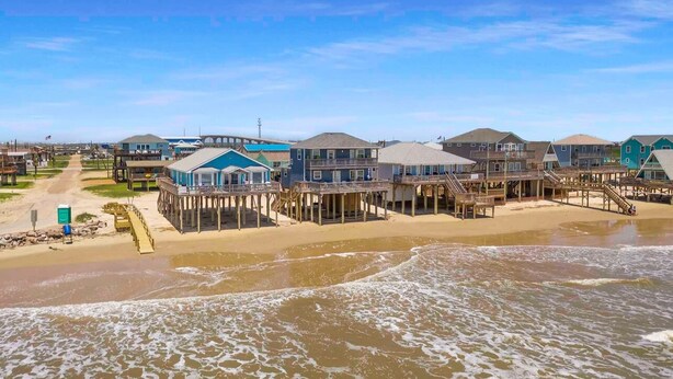 A beachfront property with multiple wooden structures connected by walkways, a sandy beach, and a clear view of the ocean. - House and Toes in the SAND. No cars on this beach area! Vacation of a lifetime! (Freeport)