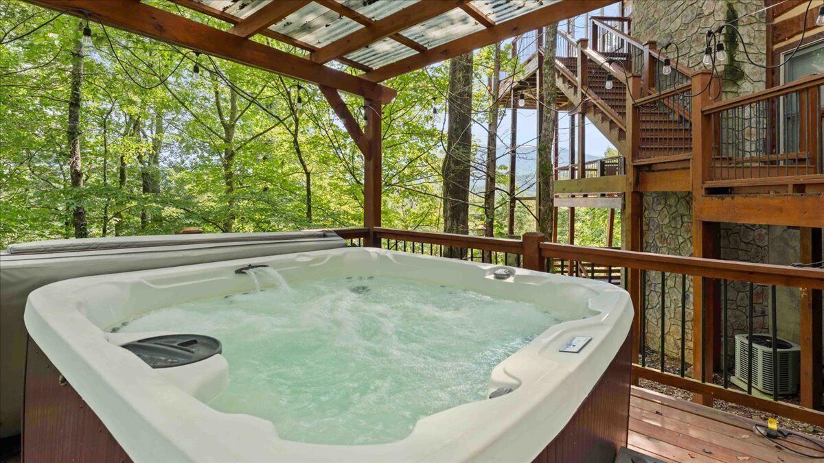 A hot tub on a wooden deck with a view of a forested area.