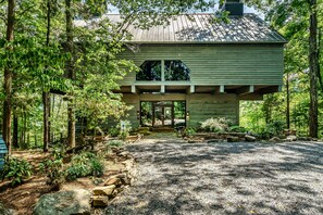 A rustic cabin with a gravel driveway, surrounded by trees and a wooden deck. - Laurel Valley Mountain Retreat (Townsend)