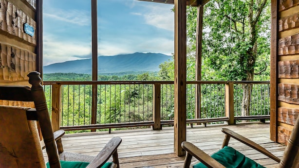 Una terraza de madera con vistas a montañas y vegetación.