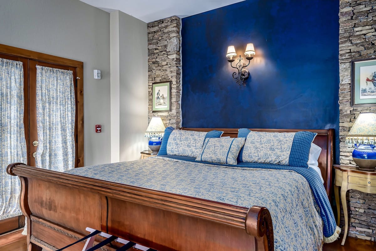 A bedroom with a wooden bed, a stone accent wall, and a blue painted wall.