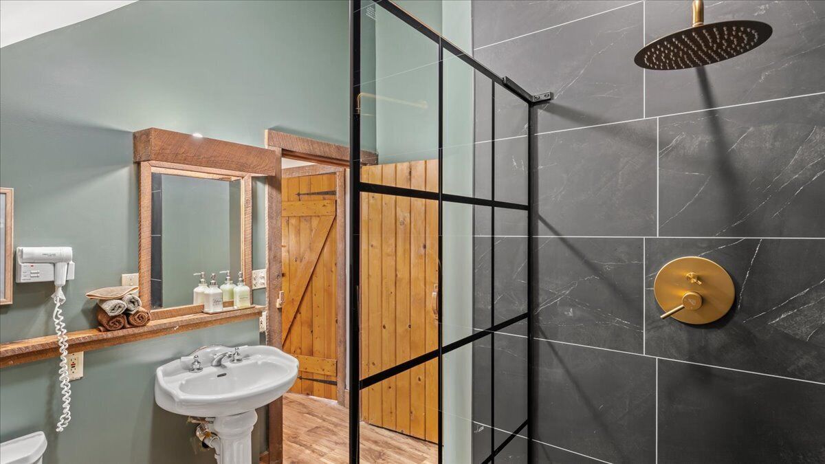 A bathroom with a glass-enclosed shower, a white sink, and a wooden vanity.