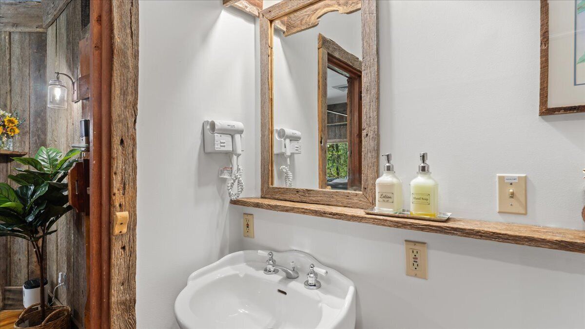 Une salle de bain avec un meuble-lavabo en bois, un grand miroir, un évier et une étagère contenant des articles de toilette.
